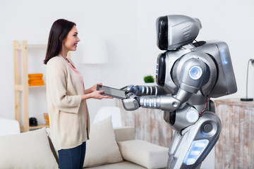 Pleasant girl giving tablet to robot 