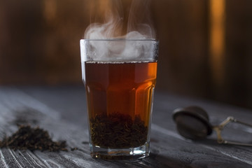 hot tea in glass with steam on wooden table