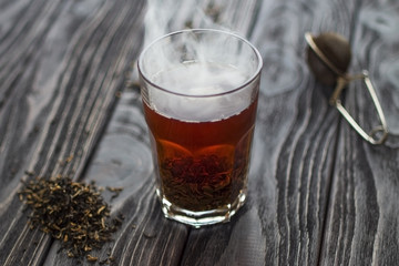 hot tea in glass with steam on wooden table