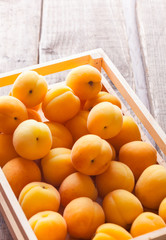 Apricots in wooden box on old rustic wooden table and bright background