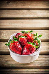 strawberries group in white ceramic bowl on rustic wooden table