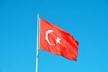 The national flag of Turkey blowing in the wind against a blue sky