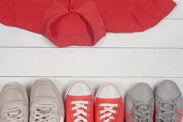 Women clothing set and accessories on a rustic wooden background. Sports T-shirt and sneakers in bright colors. Top view