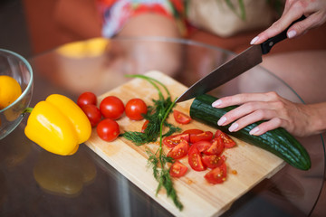 close-up woman cutting tomatoes vegetable salad on a wooden board in the kitchen