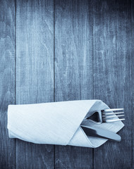 knife and fork at napkin on wood