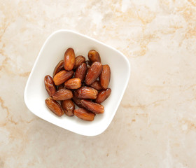 Dried dates fruit in a bowl, on a marble background