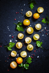Food background of sliced yellow tomatoes cherry, dark backgroun