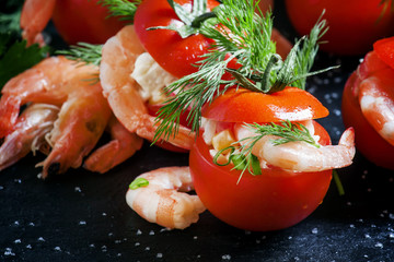 Red tomatoes stuffed with shrimp salad, black background, select