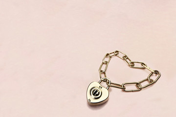 Heart shaped padlock and chain on a pink paper background