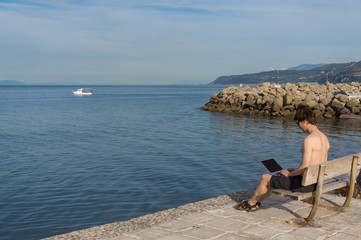 Young man and his laptop near the sea