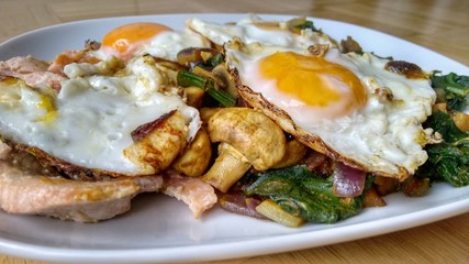 Delicious healthy meal with fried eggs, mushrooms, salmon fish and vegetables on white plate.