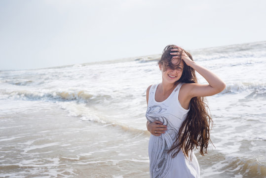 Beautiful pregnant woman smiling on the sea shore