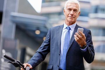 Successful businessman on bicycle with mobile phone