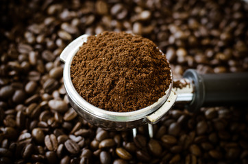 Ground coffee in brew unit on coffee bean background