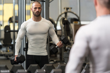 Fototapeta na wymiar Young Bodybuilder Exercising Biceps With Dumbbells