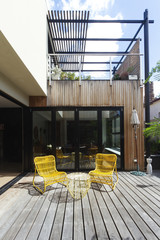 Pair of yellow cane outdoor chairs on wooden deck contemporary c