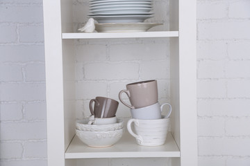 Different clean dishes on wooden shelves