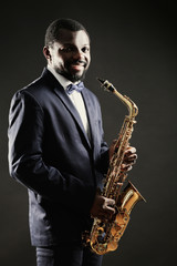 Fototapeta na wymiar African American jazz musician playing the saxophone on grey background