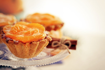 Sweet cakes with tangerines on table, close up