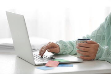 E-commerce concept. Woman with credit card, laptop and cup of coffee, close up