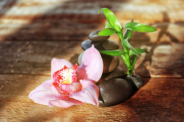 Spa stones with bamboo and pink orchid on wooden background