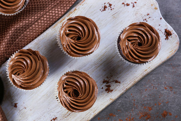 Four chocolate cupcakes on a tray over grey background, close up