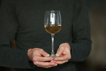 Man holding white wine in a glass, close up