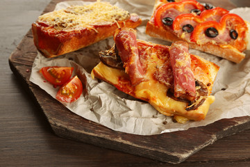 Hot pizza baguettes with bacon, salami and ham on wooden table