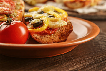 Hot pizza baguette with olives, paprika and salami on wooden table