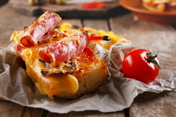 Hot pizza baguette with bacon, mushrooms and cheese on wooden table