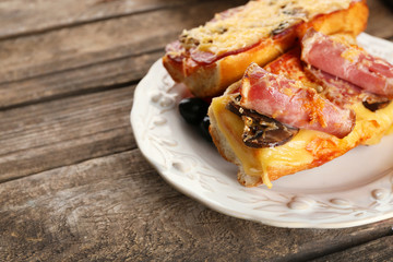 Hot pizza baguettes with bacon, salami and mushrooms on wooden table