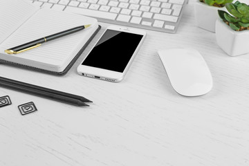 Workplace with mobile phone, computer peripherals and stationery on light table