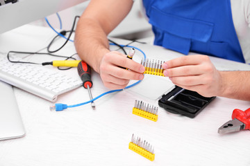 Young repairer with different tips for screwdriver in service center