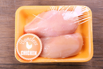 Packed pieces of chicken meat on wooden background