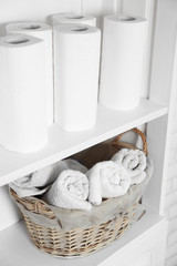 Fototapeta na wymiar Bathroom set with towels and basket on a shelf in light interior