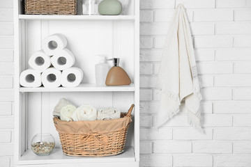 Bathroom set with towels, dispensers and basket on a shelf in light interior