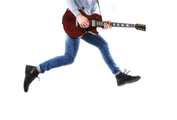 Crazy young man in blue jeans playing electric guitar, isolated on white