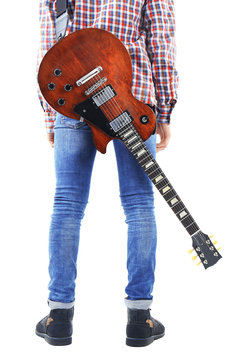 Young man in blue jeans standing back with electric guitar, isolated on white