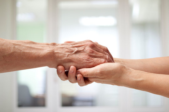 Hands of an elderly man holding the hand of a woman