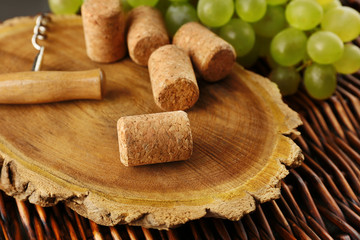 Wine corks and tailspin with bunch of grapes on wooden background