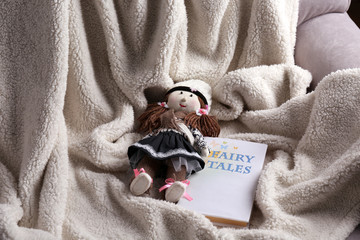 Rag doll with fairy tales book on  bedspread. Childhood concept