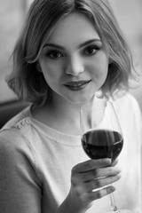 Young woman with glass of red wine in shades of grey