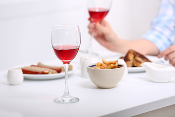 Dinner with glasses of wine on light blurred background