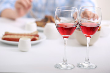 Dinner with glasses of wine on light blurred background