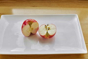 Red Apple cut in Half on White Plate