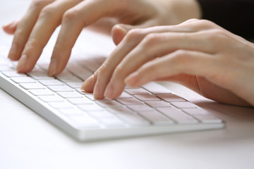 Fototapeta na wymiar Female hands using keyboard on white wooden table, close up