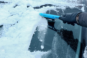 Removing snow from car windshield, closeup