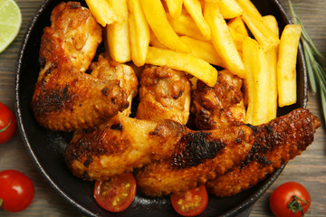 Baked chicken wings with French fries, close up