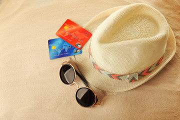 Bank card with male hat and sunglasses on sand background © Africa Studio