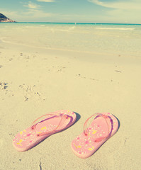 Fototapeta na wymiar slippers on sand retro effect